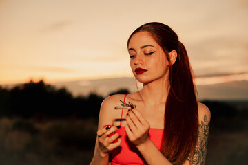 Girl in a red dress smoking a marijuana joint during sunset