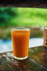 A glass of freshly squeezed tangerine juice on a wooden countertop.
