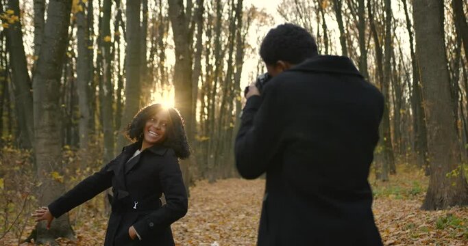 Black couple taking photos in an autumn park