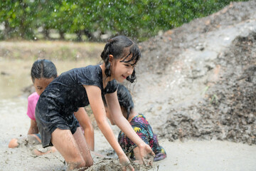 Little girls have fun playing in the mud in the community fields
