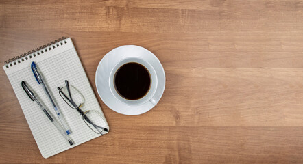 Cup of coffee on the table with the supplies for office work, coffee at work concept, copy space, top view