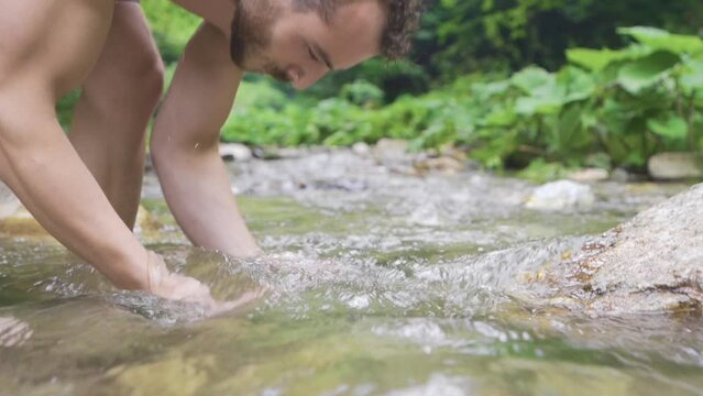Man washing his face in stream water. Slow motion.
Man washing face in stream in nature.
