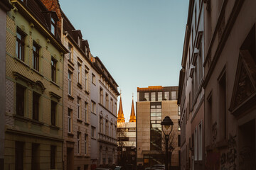 Fototapeta na wymiar Blick auf Kirche zwischen Häusern bei Sonnenuntergang in Bonn eine Großstadt in Nordrhein-Westfalen
