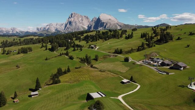 Seiser Alm Alpe di Siusi and Chalet in Dolomites near Compatsch, Compaccio Italy. Sassolungo and Sassopiatto mountai range, Langkofel and Plattkofel aerial view. South Tyrol Trentino Alto Adige, Italy