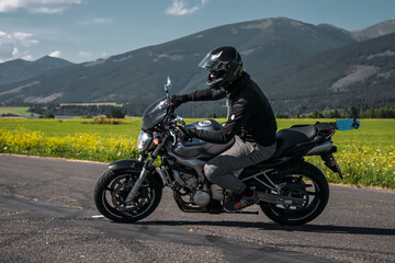 Motorbike riding on empty road with hill and field in background. Motorcycle sport.