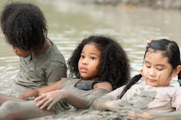 Little girls have fun playing in the mud in the community fields