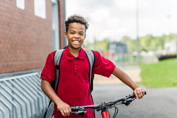 Smiling african american school boy with backpack and bike