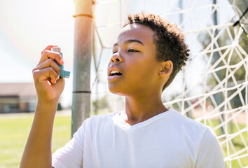 Child is using an asthma inhaler in park - obrazy, fototapety, plakaty