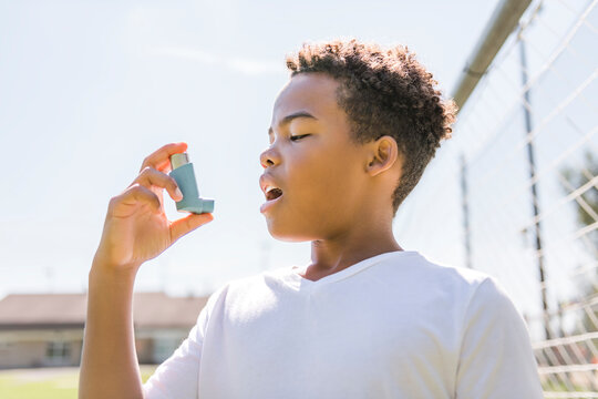 Child is using an asthma inhaler in park