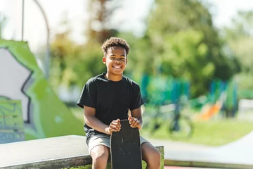 Rollo Afro-American boy with black t-shirt posing with his skateboard with the sky in the background © Louis-Photo