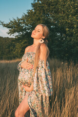 portrait of beautiful happy pregnant woman in countryside during sunset