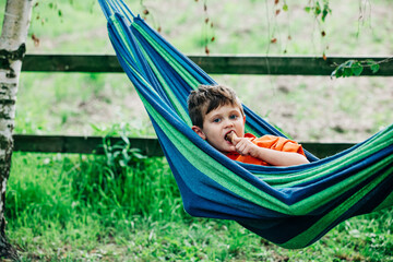 Little boy with ice-cream in hammock in village outdoor