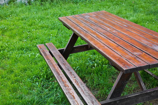 Wooden empty  picnic table on a green meadow of a public park