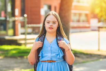 portrait of trisomy 21 child girl outside on a school playground
