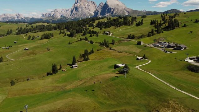Seiser Alm Alpe di Siusi and Chalet in Dolomites near Compatsch, Compaccio Italy. Sassolungo and Sassopiatto mountai range, Langkofel and Plattkofel aerial view. South Tyrol Trentino Alto Adige, Italy