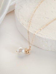 Fashion bijouterie - a thin gold chain with a pendant and a bead on a white stand