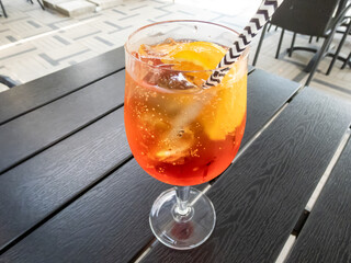 Cocktail Aperol spritz with Prosecco, aperol, soda, orange slices and ice cubes. Beautiful macro shot of orange cocktail glass covered with condenstion in sunlight