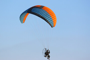 Paramotor pilot flying in a blue sky