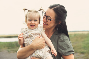 happy baby child girl and mother are playing in wheat field.