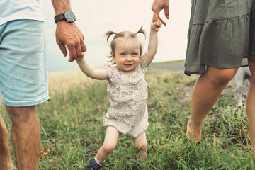 Happy family in the park. parents hold their baby hands.