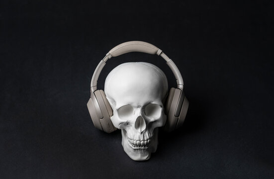halloween holiday creative concept, white skull in headphones listening to music