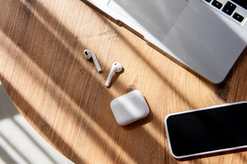freelance work environment. laptop, phone, headphones on a wooden table.