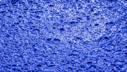 Fototapeta na wymiar Blue background, Monochrome blue texture. Selective focus. Dried liquid paint, construction waste. Small craters on blue background