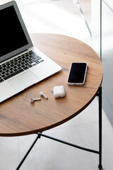 freelance work environment. laptop, phone, headphones on a wooden table.