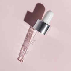 Pipette with dose of fluid hyaluronic acid on pink background. Cosmetics concept.
