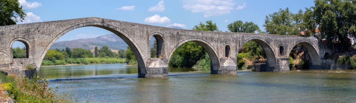 The Bridge of Arta. A stone bridge that crosses the Arachthos river  in the west of the city of Arta in Greece. Sunny day with blue sky