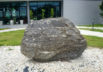 A big gneiss metamorphic rock stone on outdoor garden decoration.