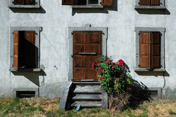 Fototapeta na wymiar Traditional old house facade with red roses in Les Houches, Chamonix, France