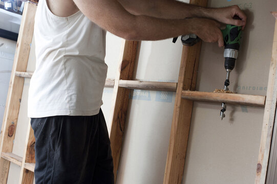 Man Drilling A Stud Wall During Construction