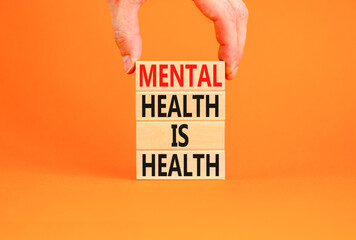 Mental health psychological symbol. Concept words Mental health is health on wooden blocks on a beautiful orange table orange background. Psychologist hand. Psychological mental health concept.