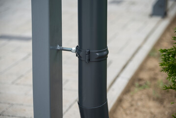 Downspout bracket and pipe welded on a post