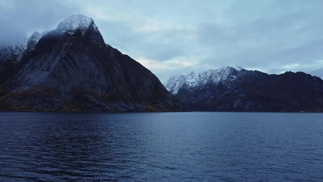 Rocky mountain ridge and wavy sea against gloomy sky in Norway