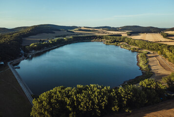 Aerial photo of the peaceful and idylic blue lake on sunset. Drone shot from above - trees and blue lake in Europe - Slovakia.