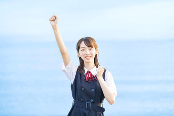 海を背景に、笑顔を見せる女子高生 