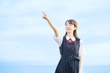 海を背景に、笑顔を見せる女子高生 