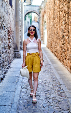 Cheerful stylish woman walking along paved street