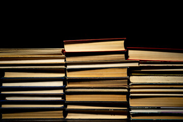 Stacks of books in red, blue, green covers on black isolated background. Rows of old books with paper pages. Literature. Textbooks for learning, gaining knowledge. Collection of literary archive.