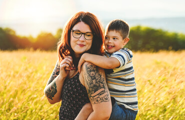 Portrait of a little boy with down syndrome in sunset on summer season with his mother