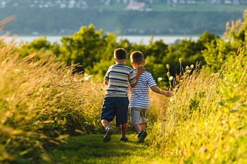 Portrait of a little boy with down syndrome in sunset on summer season with his brother