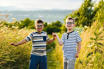 Portrait of a little boy with down syndrome in sunset on summer season with his brother