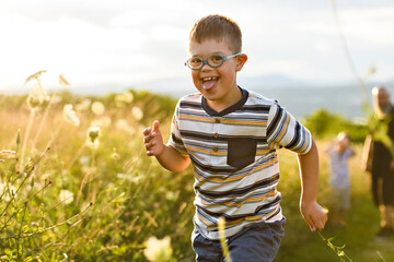Portrait of a little boy with down syndrome in sunset on summer season