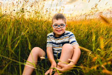 Portrait of a little boy with down syndrome in sunset on summer season