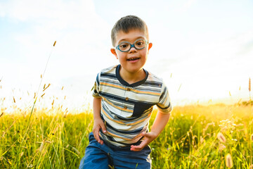 Portrait of a little boy with down syndrome in sunset on summer season