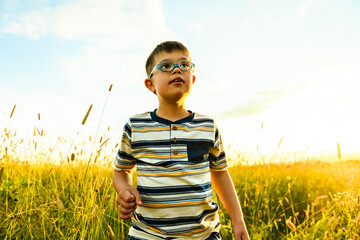 Portrait of a little boy with down syndrome in sunset on summer season