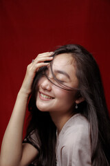 Asian woman taking photo on a red background. Happy Asian woman. Beautiful asian woman with long and straight hair.