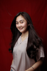 Asian woman taking photo on a red background. Happy Asian woman. Beautiful asian woman with long and straight hair.